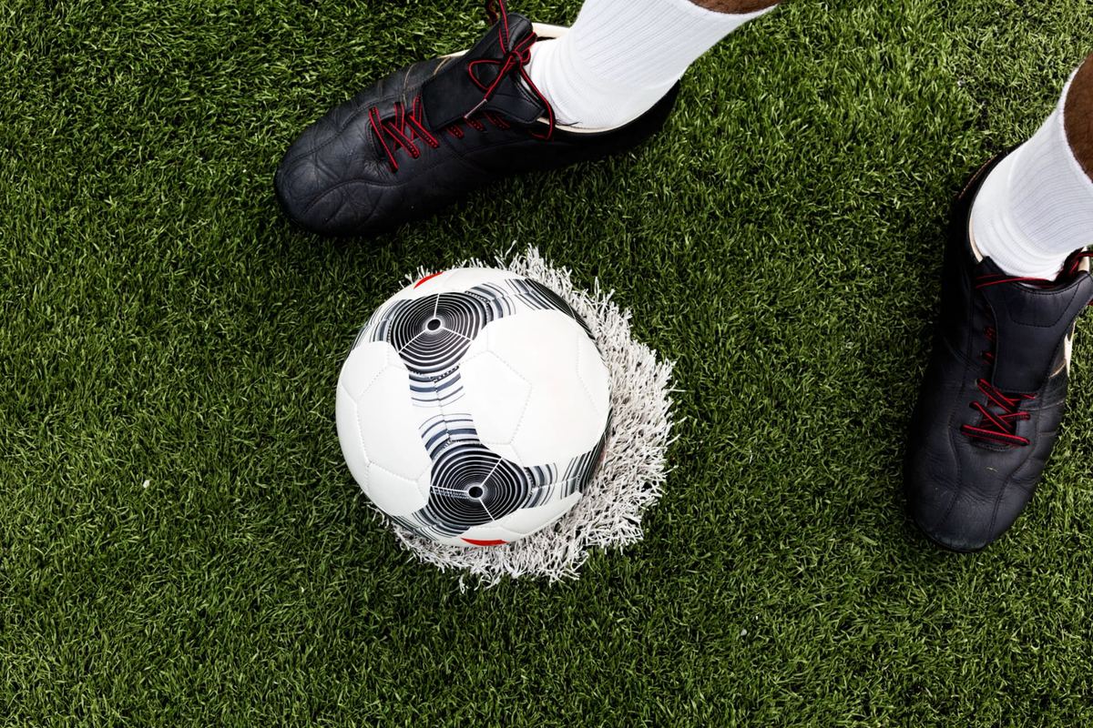 Female footballer striking a ball on a floodlit pitch